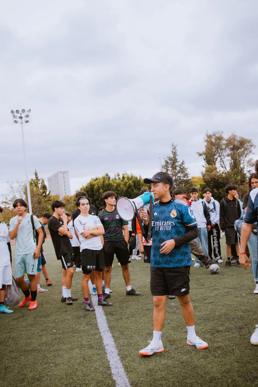 Coach leading a football training session with teenage athletes