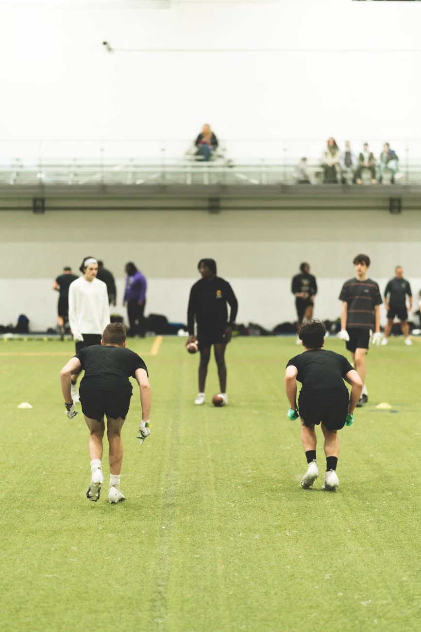 Athletes practicing football drills indoors